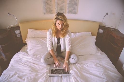 ベッドの上でパソコンを操作する女性